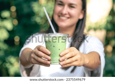 Iced green tea with milk in woman hand.