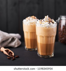 Iced Latte Coffee In A Tall Glass With Caramel And Chocolate Syrup And Whipped Cream. Dark Wooden Background.