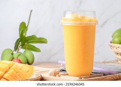 Iced Mango Smoothie. In A Clear Plastic Cup. Decorate Background With Fresh Mangoes. With Space For Text.