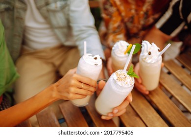 Iced milkshake. Young friends drinking milkshakes in a cafe. Summer refreshing drinks. Friendly lunch. - Powered by Shutterstock