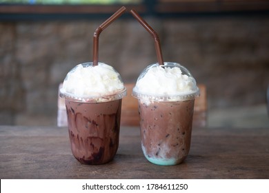 Iced Mint Chocolate Drink And Iced Chocolate Drink In Plastic Glass On Wood Table