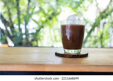 Iced Mocha Coffee In A Transparent Glass On Wooden Saucer With Homemade Ice