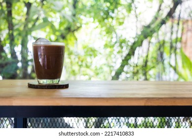 Iced Mocha Coffee In A Transparent Glass On Wooden Saucer With Homemade Ice