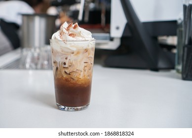 Iced Mocha Cola Latte. A Glass Of Coffee Mixed With Cocoa Syrup And Cola Drink, Topped With Whipped Cream On White Table.