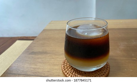 Iced Orange Americano With Spherical Ice On A Wooden Table