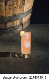 Iced Pink Lemonade Drink In Tall Glass On Concrete Floor Next To Whiskey Bar