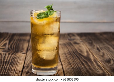 iced tea with lemon and fresh mint on wooden background