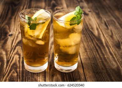 iced teae with lemon and fresh mint on wooden background