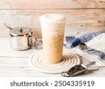 Iced Tieguanyin milk tea or Tie guan yin milk tea with sugar pot and spoon served in disposable glass isolated on table side view of hong kong tea