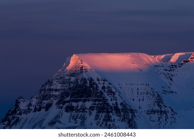 Iceland. Beautiful snowy mountain with pink sunset in background. Mountain is covered in snow and has stunning view. Sun is setting behind mountain, casting warm glow on snowy landscape - Powered by Shutterstock