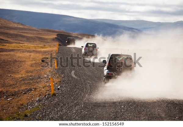 Iceland black road with\
cars making dust