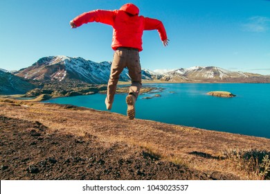 Iceland experiential travel photography, young active man leaping with beautiful snow covered mountains and lake in the background - Shutterstock ID 1043023537