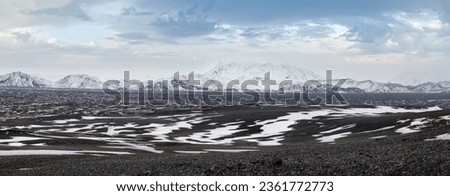 Iceland highlands autumn ultrawide view. Lava fields of volcanic sand in foreground. Hrauneyjalon lake and volkanic snow covered mountains in far.