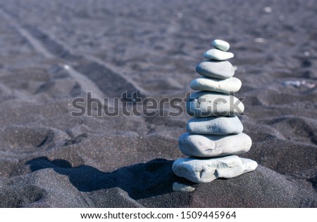 ICELAND: Jokulsarlon lagoon, Amazing cold landscape picture of icelandic glacier lagoon. Close up picture of a stone cairn on black volcanic beach. Iceland, Europe.