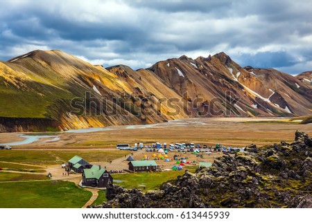 Iceland in July. Great Valley Park Landmannalaugar, surrounded by mountains of rhyolite and unmelted snow. In the valley built large camp. The concept of world tours. Trend 