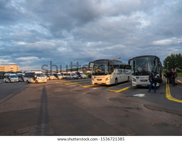 Iceland,\
Reykjavik, August 5, 2019: parked waiting buses of Reykjavik\
excursions and cars at BSI Bus Terminal in summer sunset evening.\
BSI is the main bus terminal in\
Iceland.