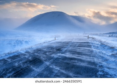 Iceland. Snowy road with mountain in background. Road is covered in snow. Sky is cloudy and temperature is cold - Powered by Shutterstock