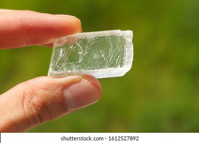 Iceland spar, a colorless and transparent mineral crystal held in a hand