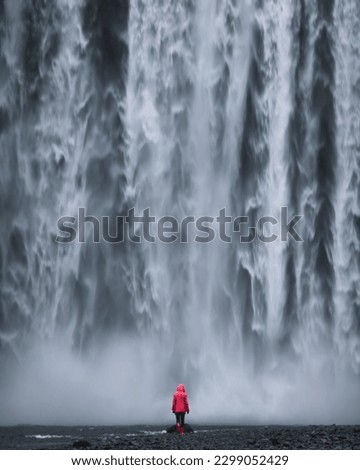 Iceland waterfall Skogafoss powerfull water wall with walking lone girl in front