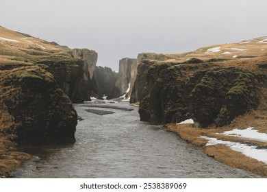 Icelandic canyon with a flowing river, mossy cliffs, and winter snow patches, showcasing the rugged and serene beauty of nature. Perfect for travel, nature, and adventure projects. - Powered by Shutterstock