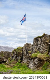 Icelandic flag flowing in the air with green grass around it