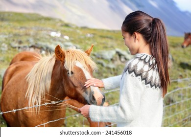 Icelandic horses - woman petting horse on Iceland. Girl in sweater going horseback riding smiling happy with horse in beautiful nature on Iceland. - Powered by Shutterstock