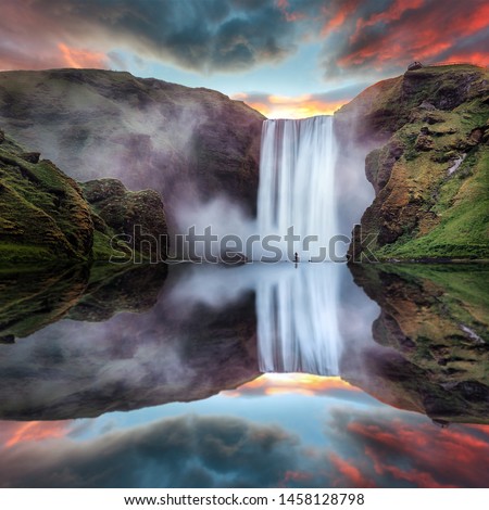 Icelandic Landscape. Classic long exposure view of famous Skogafoss waterfall with reflections. Dramatic Scenery of Iceland during sunset. majestic Skogafoss Waterfall in countryside with colorful sky