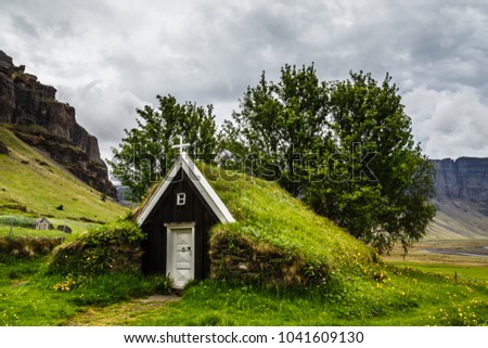 Icelandic traditional turf church covered with grass,  trees and rocks in the background near Kalfafell vilage, South Iceland