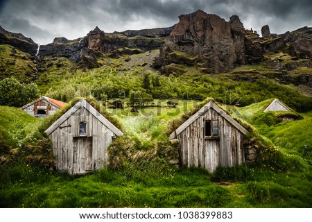 Icelandic turf houses and rocky canyon with waterfall in the background near Kalfafell vilage, South Iceland