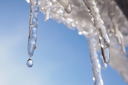 Icicle Against Light Blue Sky. Drop Of Melted Snow Falls Down. Closeup. Illustration About End Of Winter Or Beginning Of Spring. Thaw. Macro