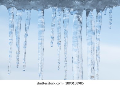 Icicle close up with detail. Ice spike hanging. Frozen water in large drop formation slowly melting and dripping. Winter wonderland concept. Freezing weather, snow, Christmas, festive background