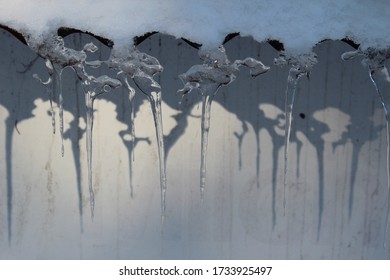 Icicles hang from rooftop with its shadow.