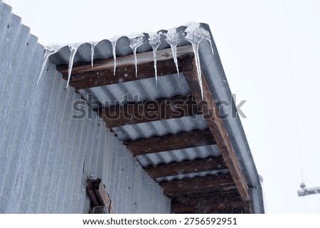Icicles hanging down on a rustic metal barn roof from corrugated metal roof