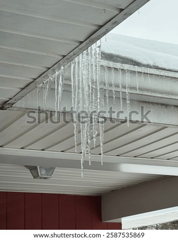 Icicles hanging from house gutter full of ice and snow