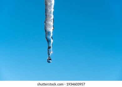 Icicles melt and drip in the spring against the blue sky.Meteorology, global warming, and melting snow and ice. Water dripping against the sky. - Powered by Shutterstock