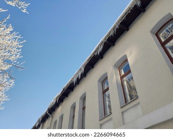 Icicles overhanging from house roof - Shutterstock ID 2266094665