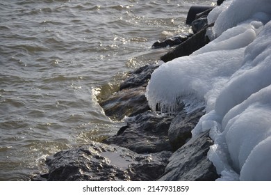 Icicles and snow melting over the rocky shoreline of the lake