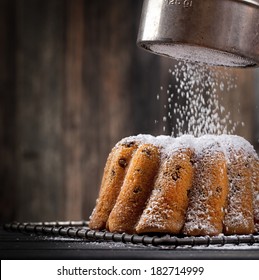 icing sugar falling on a freshly baked sweet cake, dark background