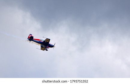 ICKWELL, BEDFORDSHIRE, ENGLAND - AUGUST 02, 2020: Extreme Aerobatics Extra EA 300L Aircraft in stunt Flight with dark sky bacground.
