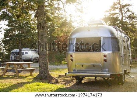 Iconic American Travel Trailer - Vintage Caravan Parked Next to Campground Picnic Table During Golden Sunset