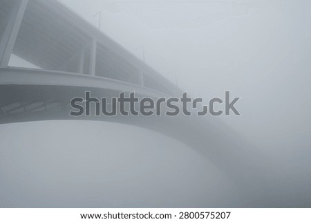 Iconic Arrabida bridge over Douro river in the middle of fog, Porto, Portugal.