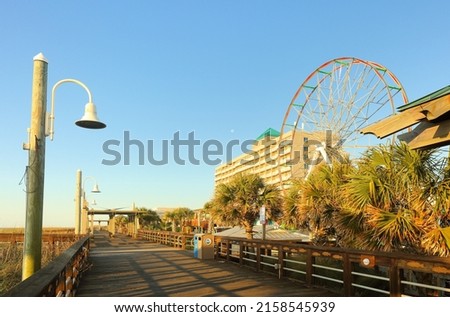 Iconic Carolina Beach Boardwalk at sunrise, Carolina Beach North Carolina USA. Boardwalk hugging a sandy beach with kid-friendly rides and snack bars, plus concerts and fireworks.