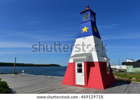 The iconic Cheticamp Harbour Lighthouse painted in the design of the Acadian flag on the Cabot Trail in Cape Breton, Nova Scotia, Canada