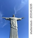 Iconic Christ the Redeemer statue in Rio de Janeiro, captured against a vivid blue sky. The upward angle highlights its grandeur and open-armed gesture, symbolizing peace and welcome.