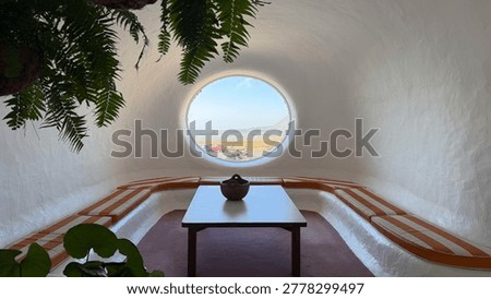 Iconic circular window framing the volcanic landscape view at the Mirador del Rio designed by Cesar Manrique with hanging plants and minimalist interior in Risco de Famara, Lanzarote, Canary Islands, Spain
