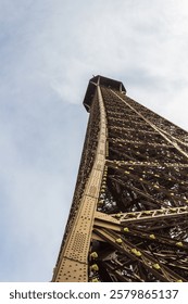 The iconic Eiffel Tower captured from a low-angle perspective, highlighting its intricate architectural details amidst a clear, bright sky.