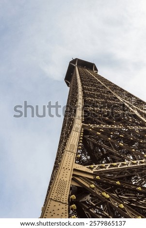 The iconic Eiffel Tower captured from a low-angle perspective, highlighting its intricate architectural details amidst a clear, bright sky.