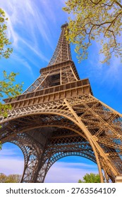 Iconic Eiffel Tower viewed from below on a clear blue sky day with spring foliage