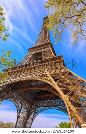 Iconic Eiffel Tower viewed from below on a clear blue sky day with spring foliage