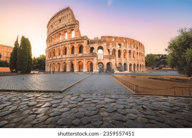 Iconic Flavian Amphitheatre, the ancient Roman Colosseum, a famous tourist landmark, illuminated at sunrise or sunset in historic Rome, Italy.